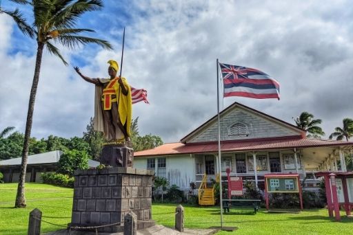 kamehameha statue with hawaiian flag flying next to it