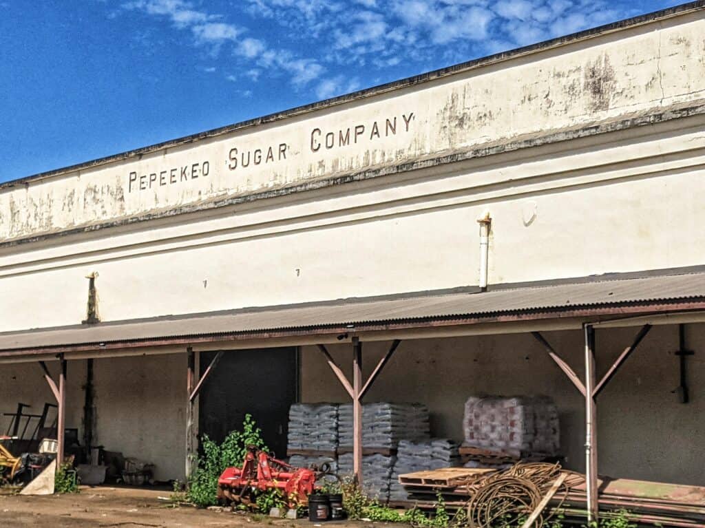 Faded sign of the historic Pepeekeo Sugar Company on an old warehouse, symbolizing the agricultural heritage of the Big Island.