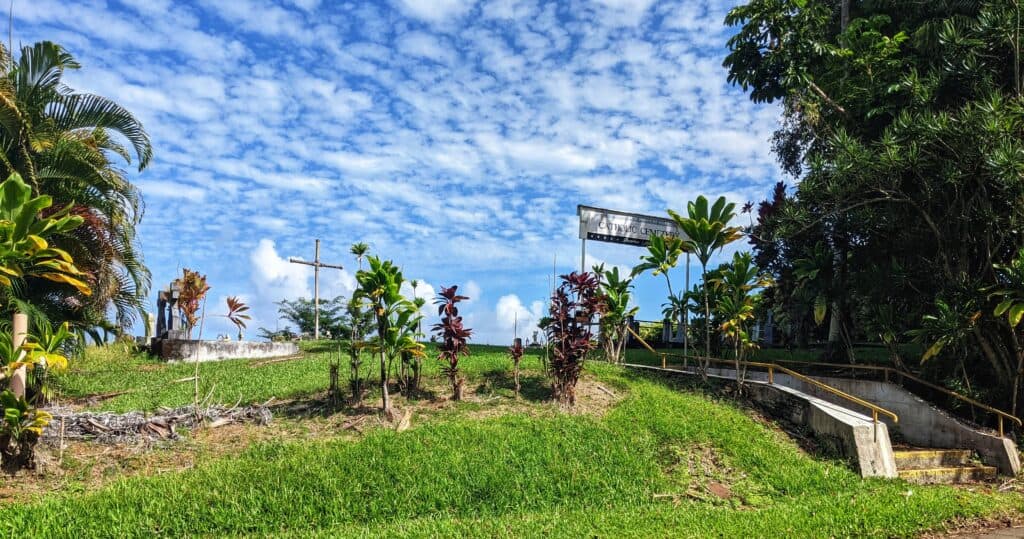 Tranquil cemetery with weathered gravestones set against a backdrop of vibrant green trees , illustrating the peaceful final resting place along Pepe'ekeo Scenic Drive.