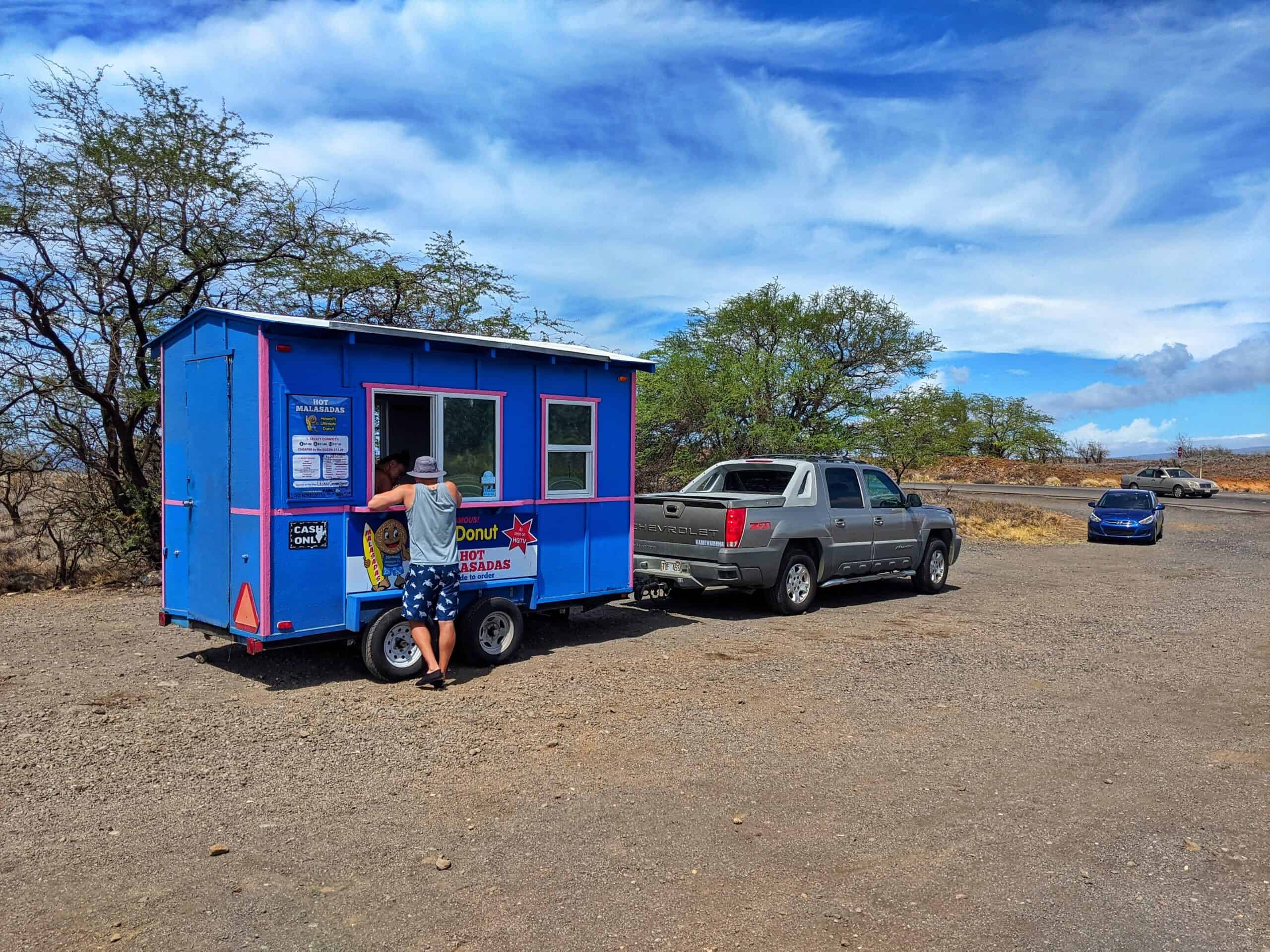 blue trailer for the hot malasadas food truck in a gravel parking lot