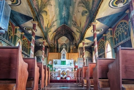 looking down the aisle inside the painted church with elaborate paintings on the ceiling and walls