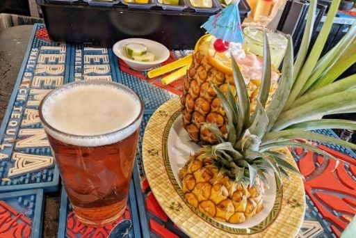 pineapples restaurant's cocktails served in a pineapple with a beer on the side