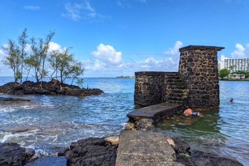 old footbridge remnant in the water with a swimmer nearby