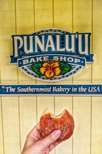 my hand holding a Malasada with a bite in it from Punalu'u Bake Shop