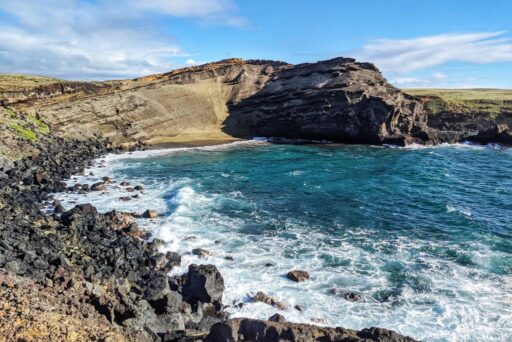 Papakolea Green Sand Beach with blue water and towering cinder cone