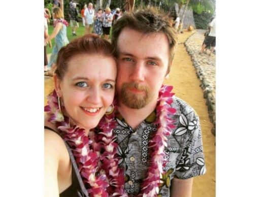 michael and i wearing traditional Hawaiian leis, with michael in a black and white aloha shirt and me in a sleeveless top.