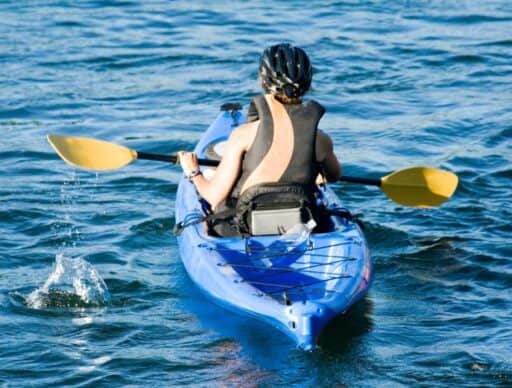 person kayaking in hawaii wearing a helmet