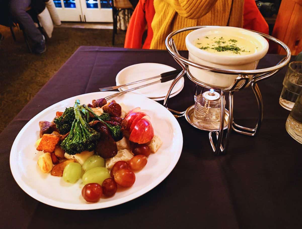 eating fondue at mozarts with plate of veggies and fruit and cheese ramekin