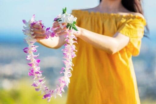 This image has an empty alt attribute; its file name is girl-in-yellow-presenting-lei-512x342.jpg