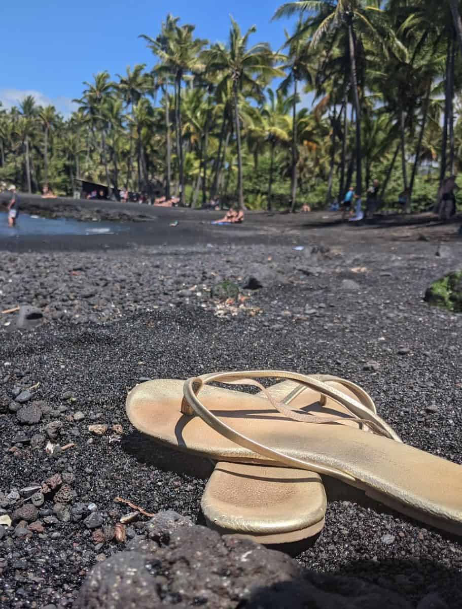 flip flops on a black sand beach in hawaii