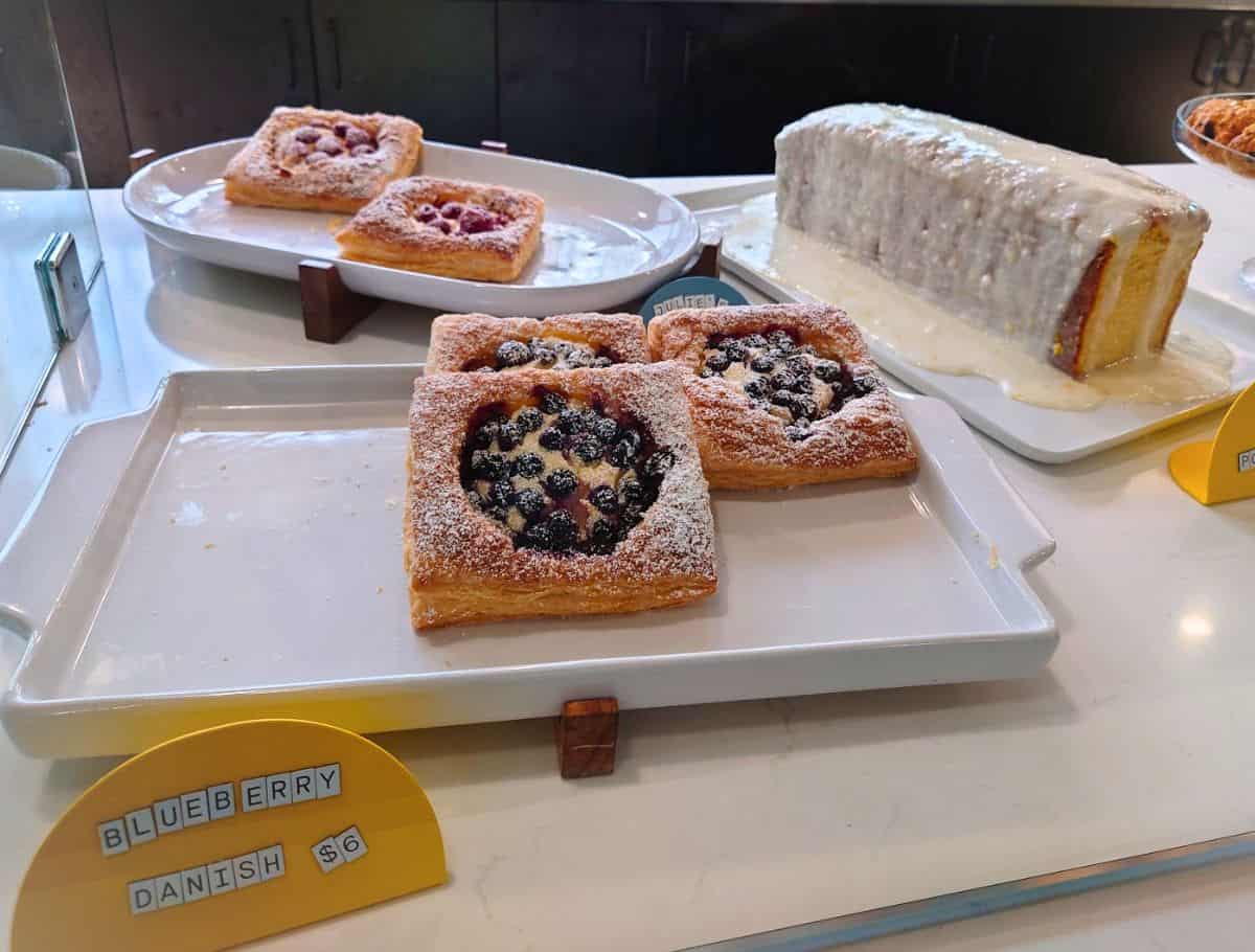 Bakery display filled with blueberry danishes, berry pastries, and thick slices of iced cake inside a Whidbey Island cafe. Fresh baked pastries paired with locally roasted drinks make this stop part of the best coffee on Whidbey Island experience.