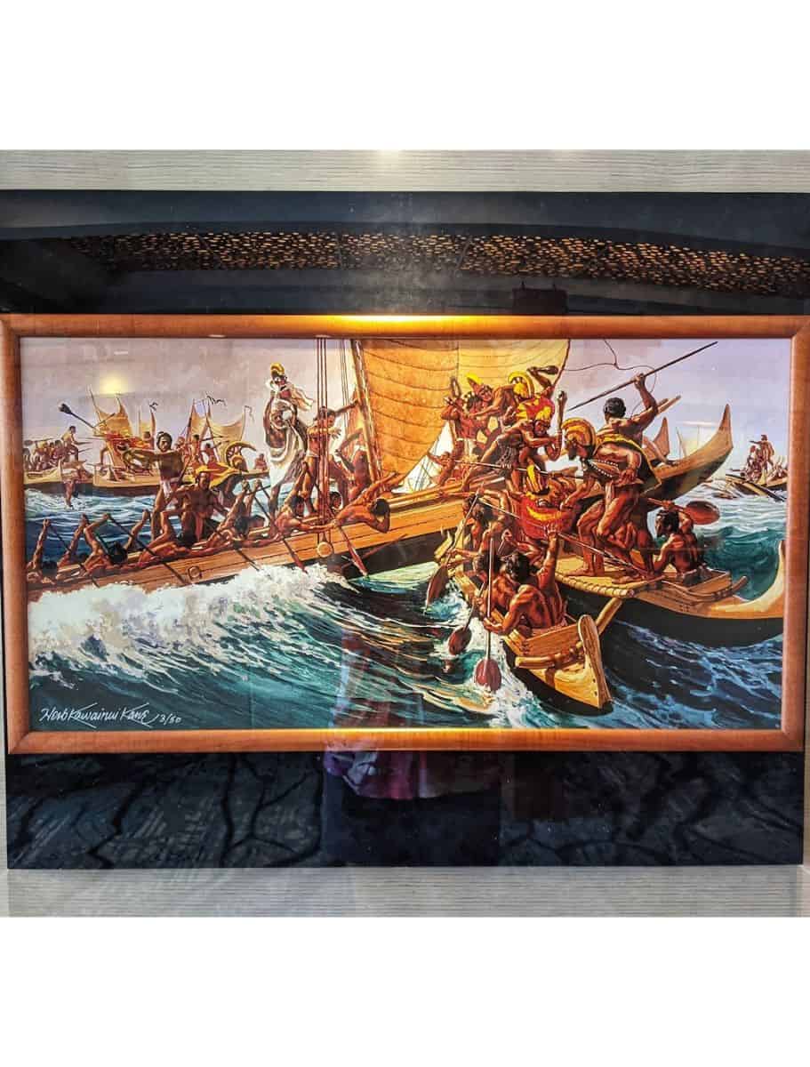 A framed painting depicting an ancient Hawaiian battle at sea, exemplifying the rich local history preserved in island galleries.