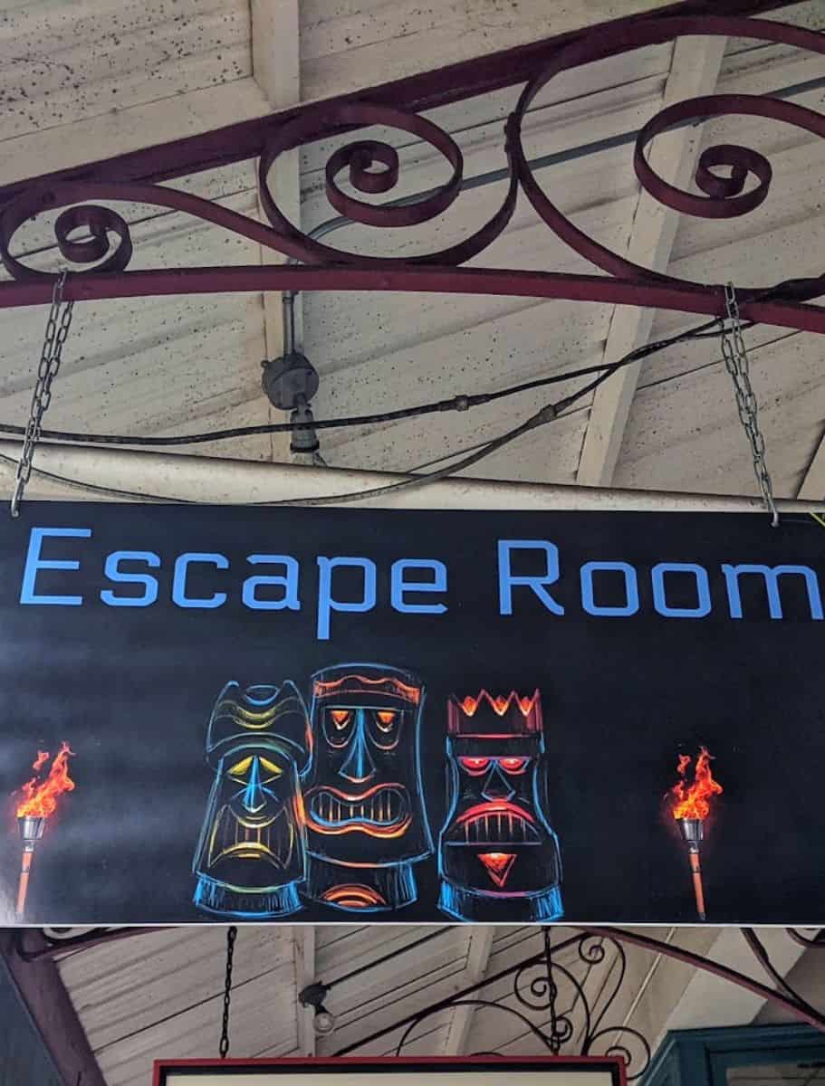 Bold 'Escape Room' sign with tiki torches and masks, indicating a fun and challenging group activity to enjoy when it's raining.