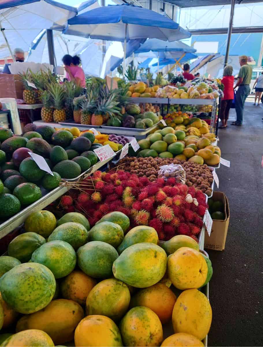 Vibrant hilo farmers market on the Big Island with fresh tropical fruits like mangoes and rambutans, a perfect rainy day visit for local produce.