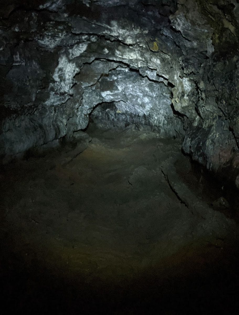 A pitch-black section of Kaumana Caves, with only the textures of the cave walls visible