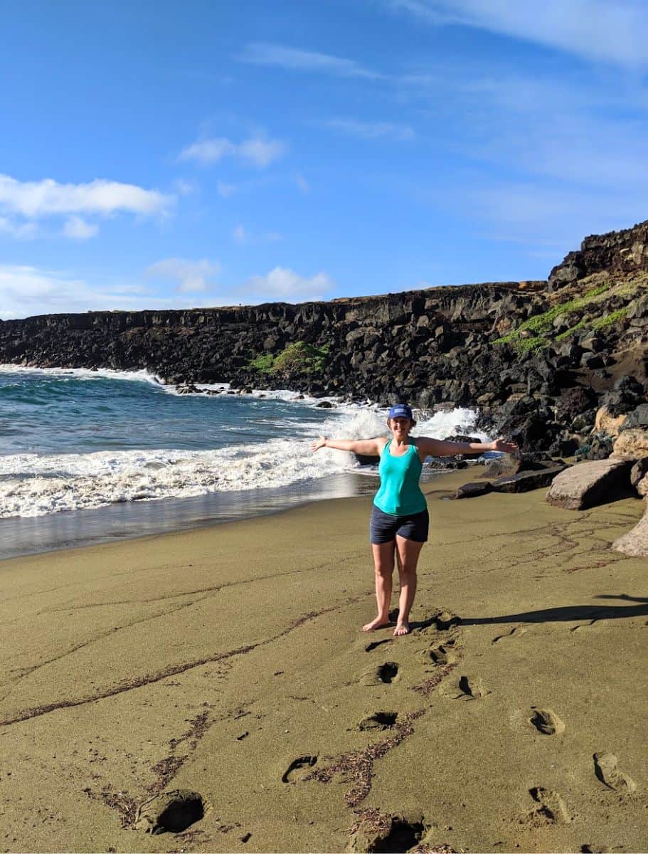 Me barefoot on Green Sand Beach with rocky cliffs and ocean behind me