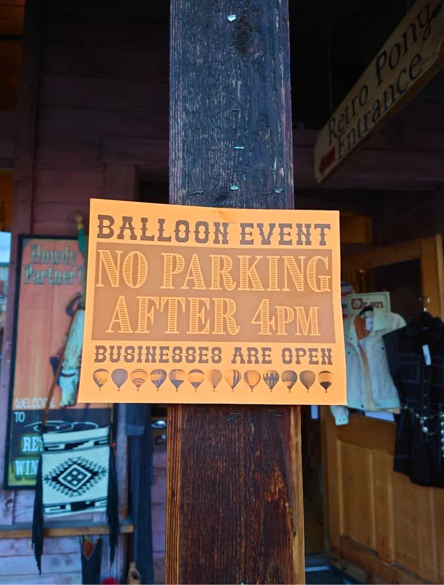 A 'Balloon Event No Parking After 4 PM' sign posted on a wooden post, with festive balloon graphics,