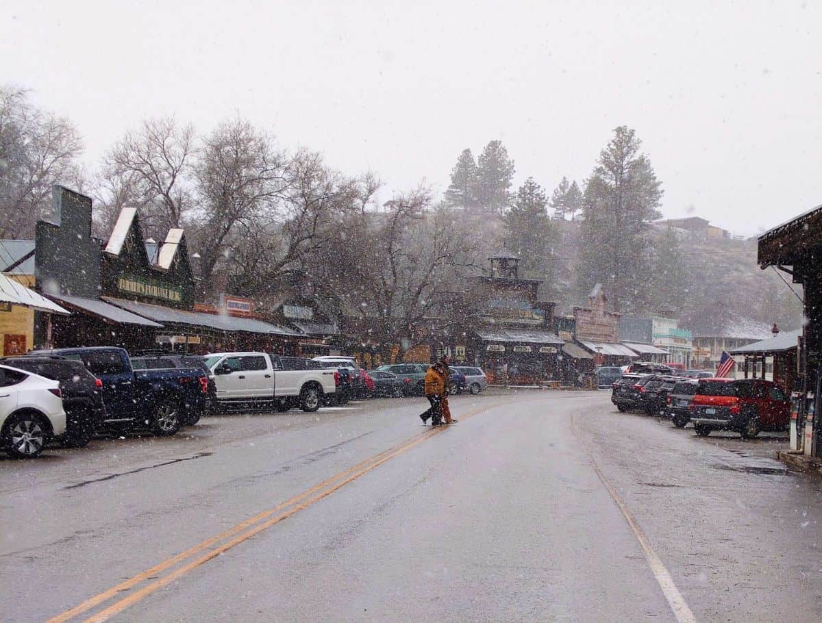 A quiet street in Winthrop with cars parked on the side and snowflakes visibly falling