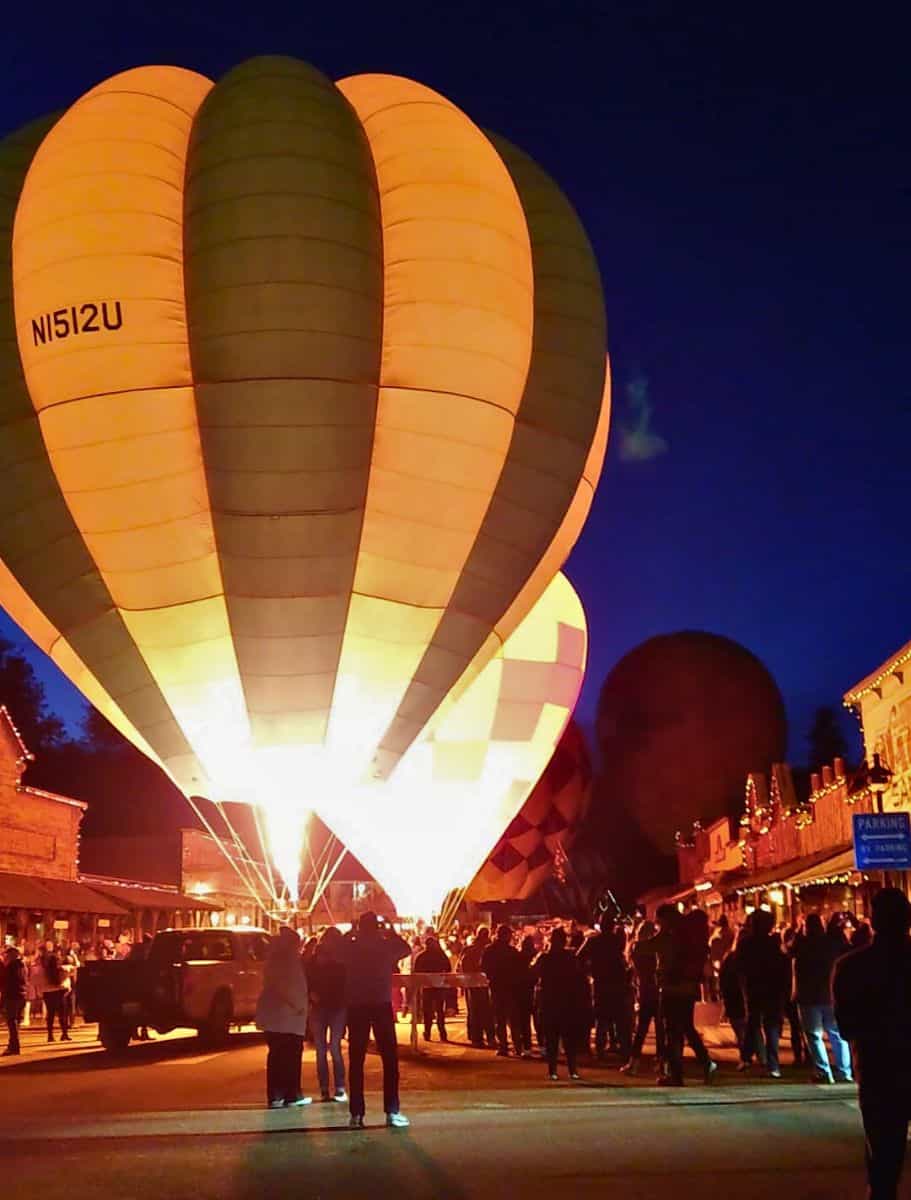Hot air balloons with bright and geometric patterns light up the evening as people crowd a Winthrop street during the Glow Up.