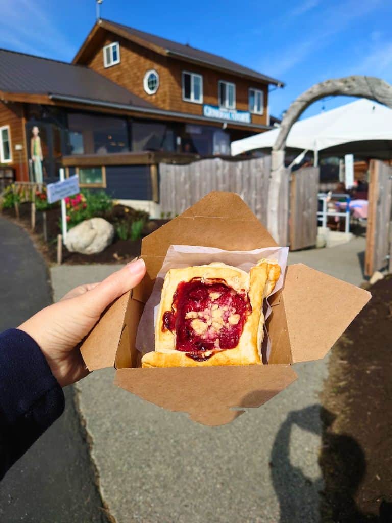 my hand holding a pastry in a box in front of Guemes Island General Store