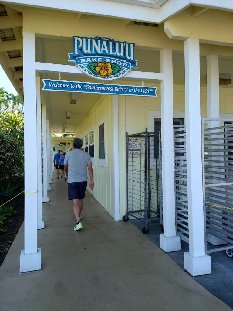 people walking down Entrance "hallway" to the yellow building of Punalu'u Bake Shop