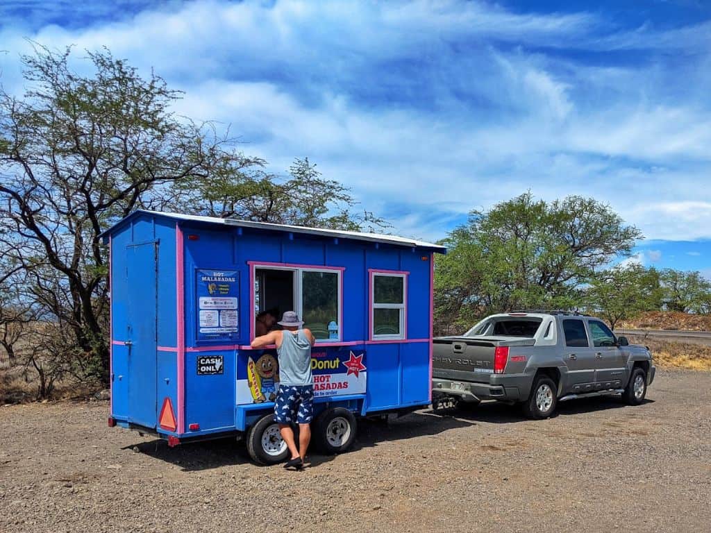 person ordering at Manuela Malasada Truck in gravel pullout on Hwy 11