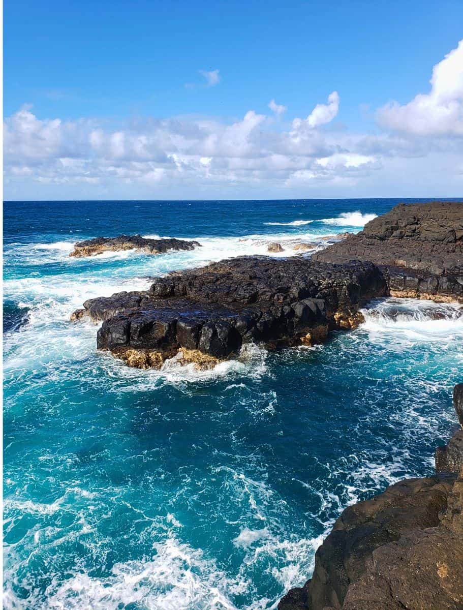rocky cliffs and boulders in churning blue ocean with lots of white foam