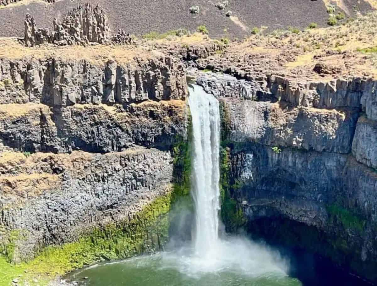 Palouse Falls falling into a green pool with deserty top