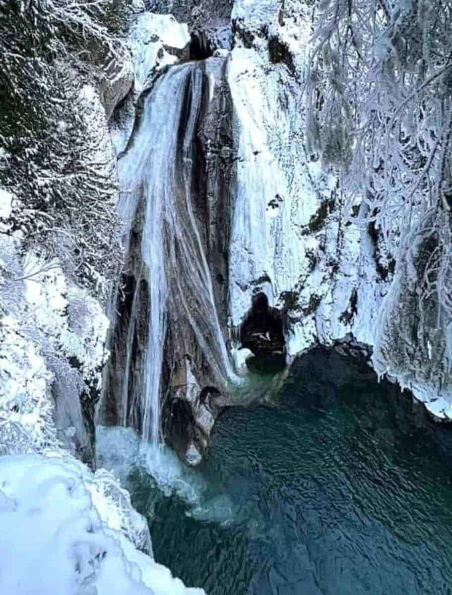 twin falls cascading into pool surrounded by wintery trees