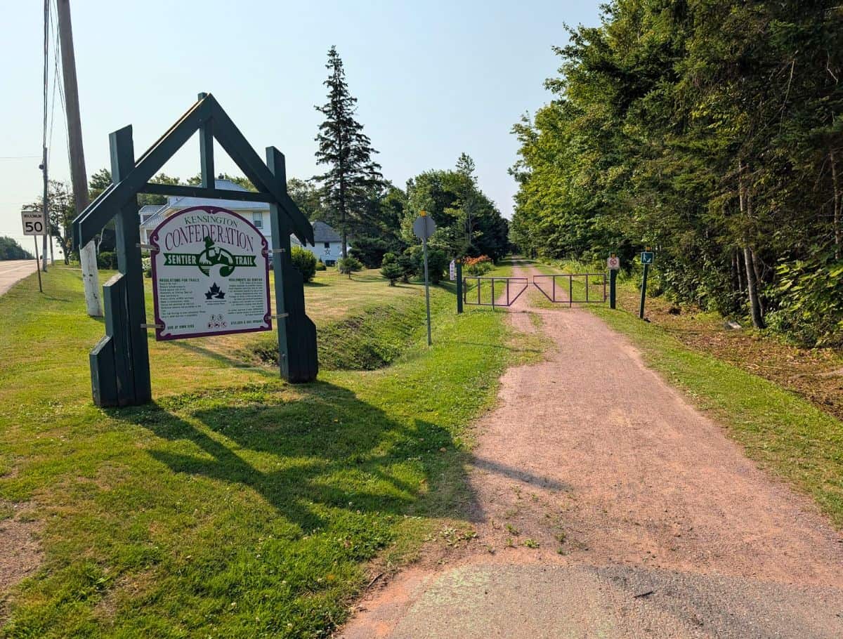 One of the entrances for the Confederation Trail with sign at the trailhead leading to a forested trail