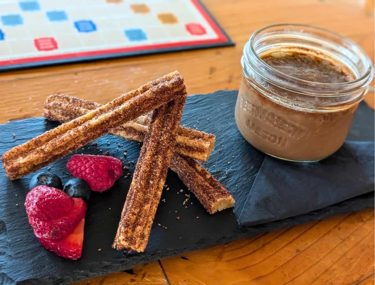 platter of Mocha crème brûlée and churros and a few fresh berries. scrabble board in background