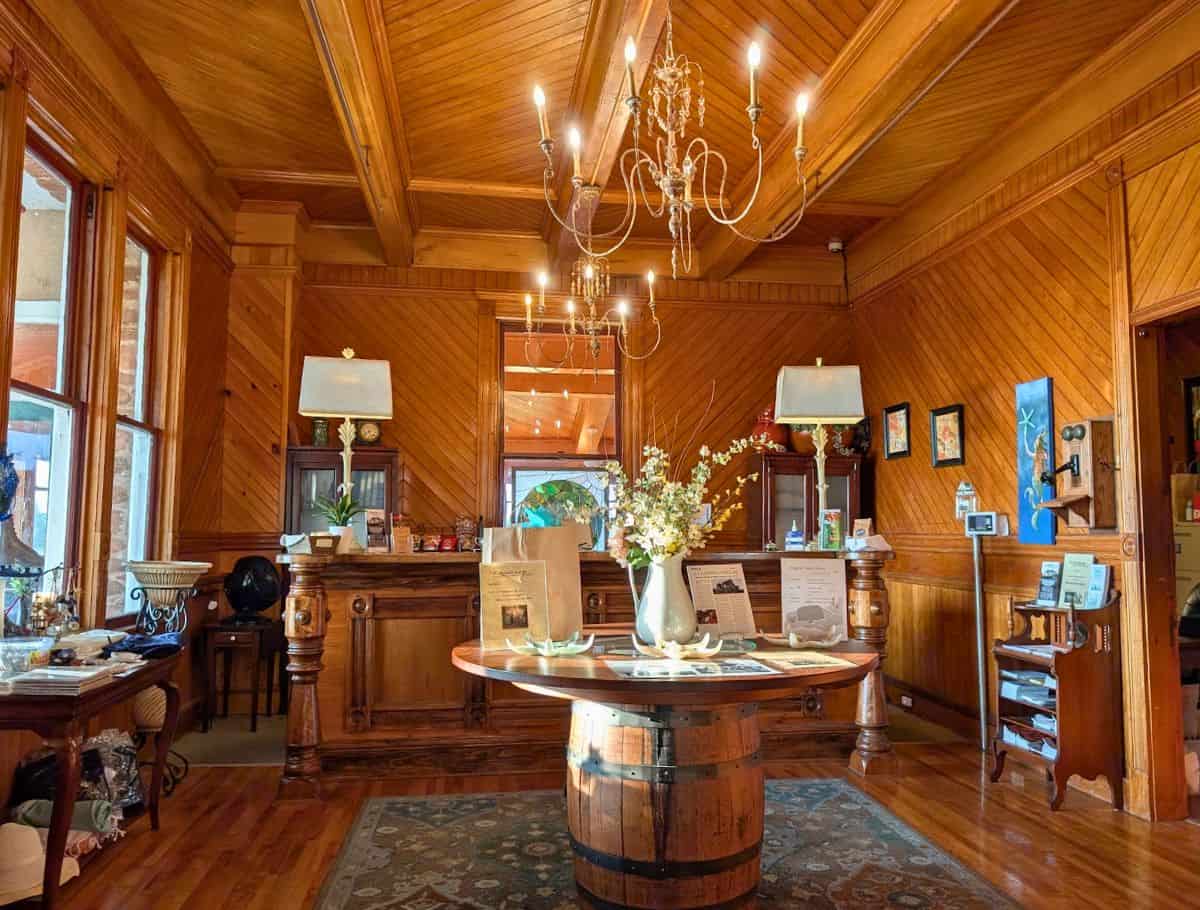 Receptionist counter and "gift shop" with wooden walls and floors and a barrel table in the middle of the room