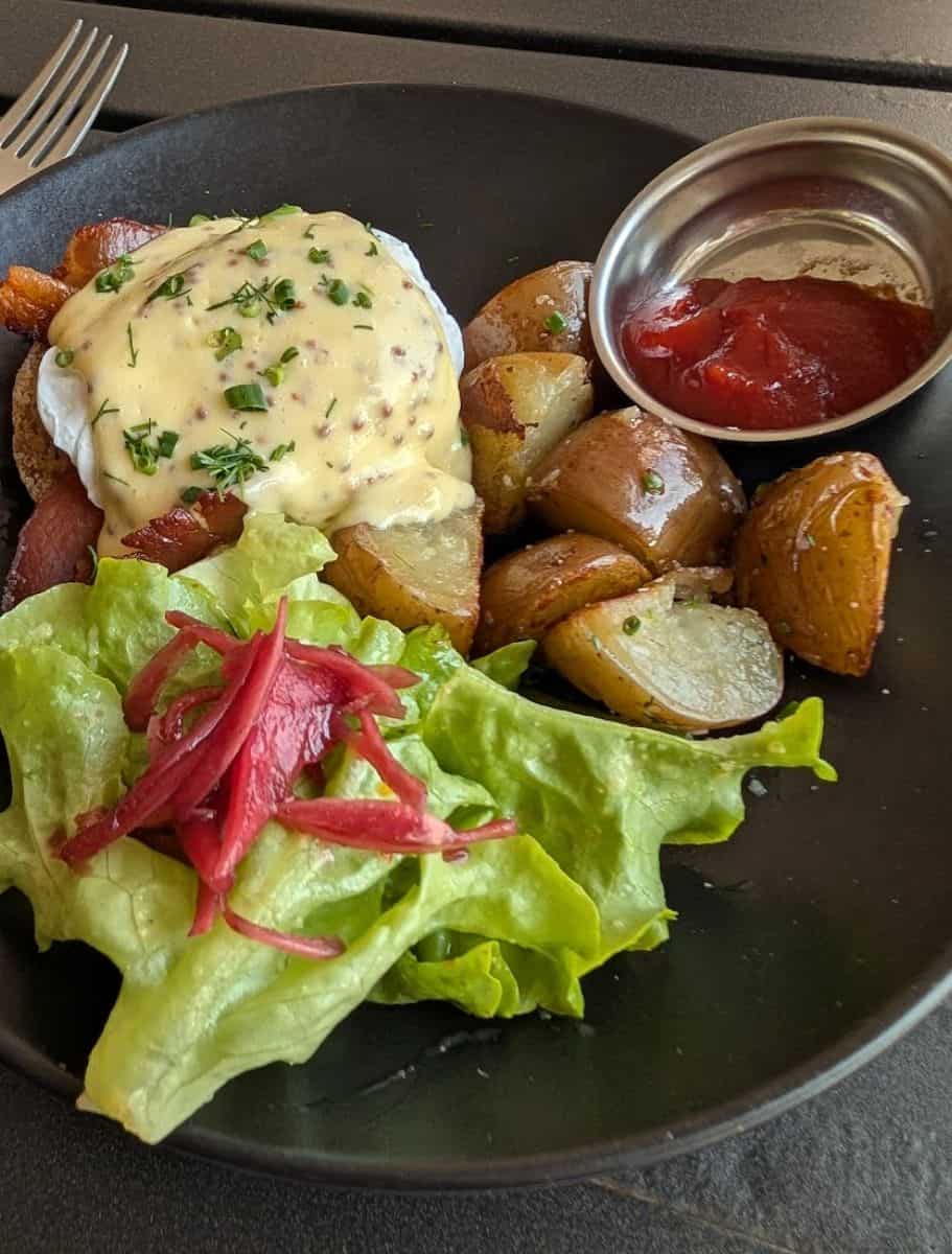 plate of eggs benedict and salad and potatoes