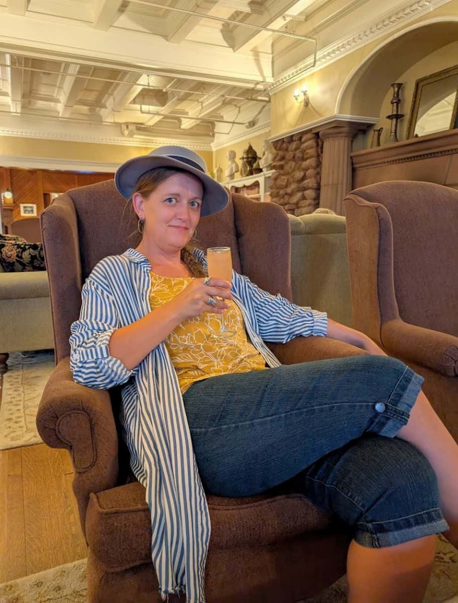 Me sitting on a wingback chair enjoying a cocktail in the library