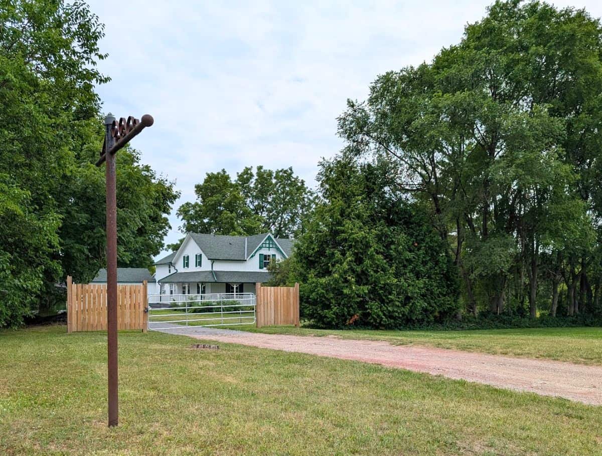 Actual house used for Green Gables, half hidden behind a wooden fence and overgrown trees