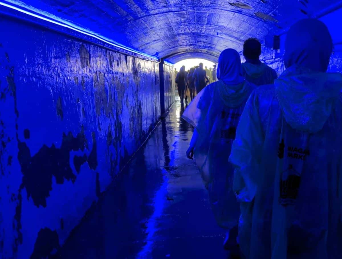 people walking the Eerie blue tunnels leading to the falls