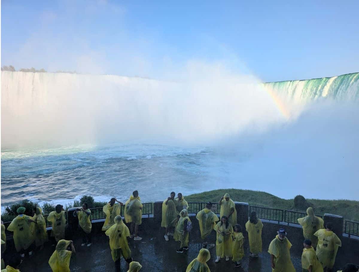 Lower level viewing platform with a bunch of poeple in yellow ponchos taking selfies with the falls