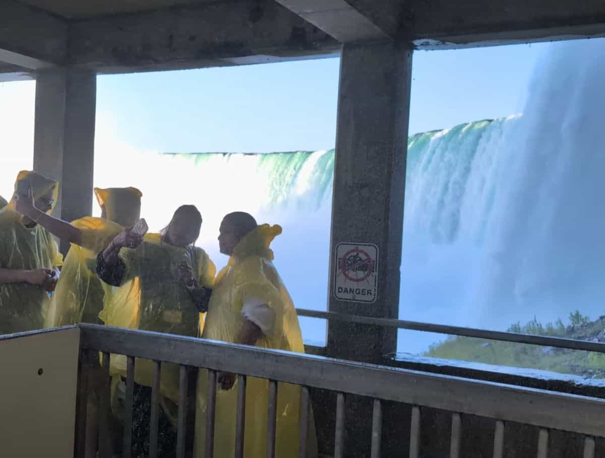 people in yellow ponchos taking selfies under the Covered viewing platform for the falls on the first level