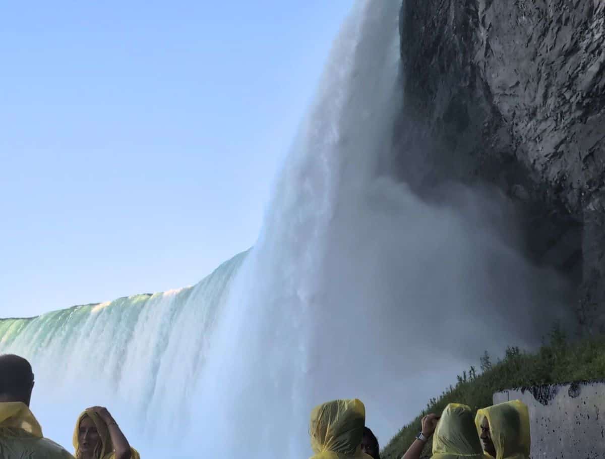 people in yellow ponchos standing super close to the edge of falls