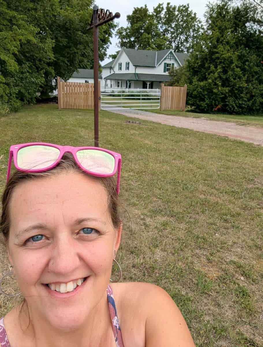 selfie of me wearing pink sunglasses on my head in front the real green gables house