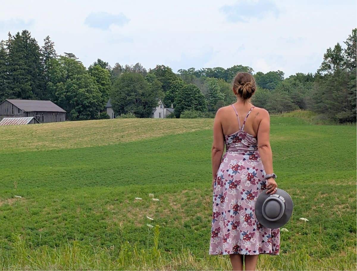 back of me wearing a dress looking towards the house across the grassy field