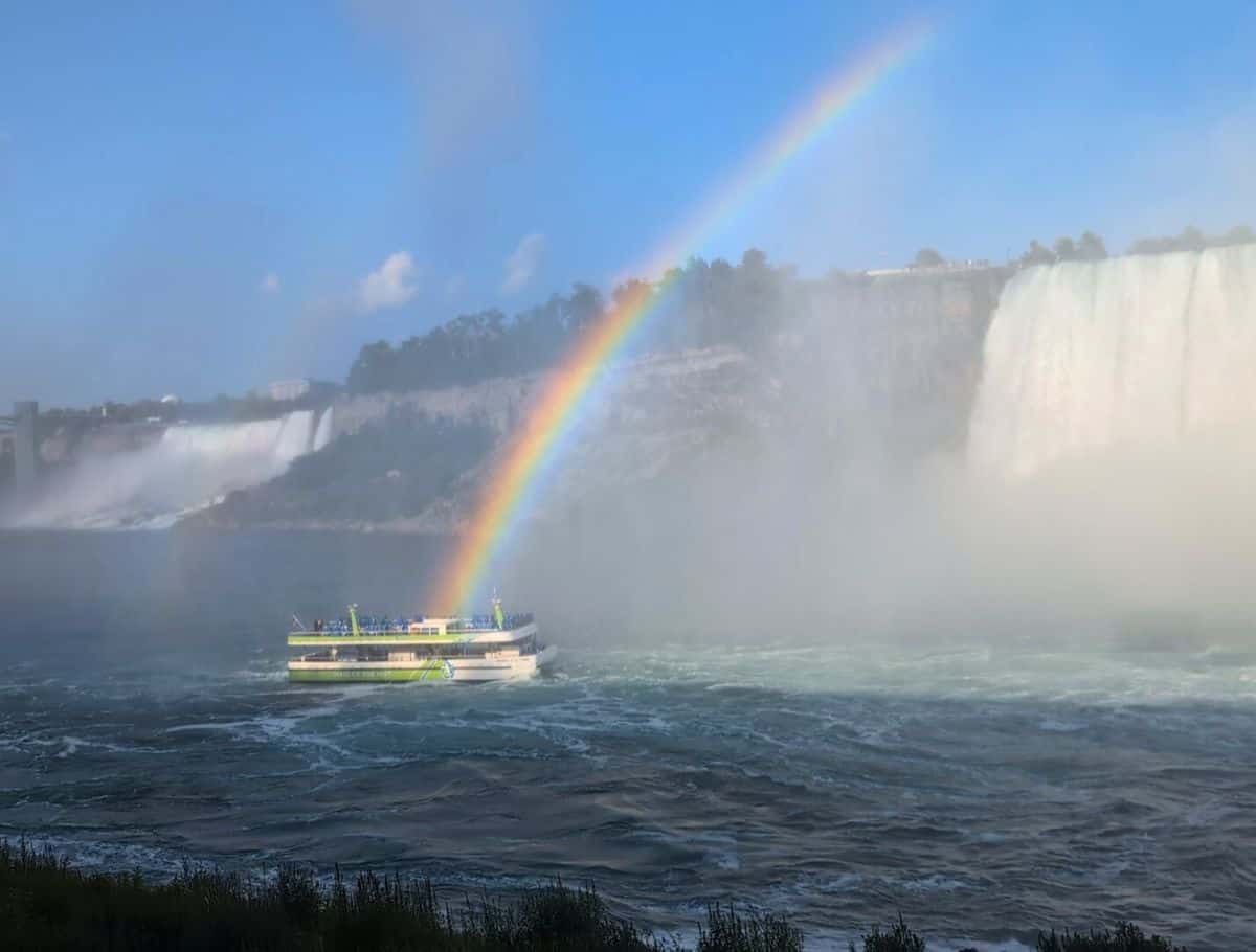 green and white Niagara boat tour at the end of the rainbow in the river