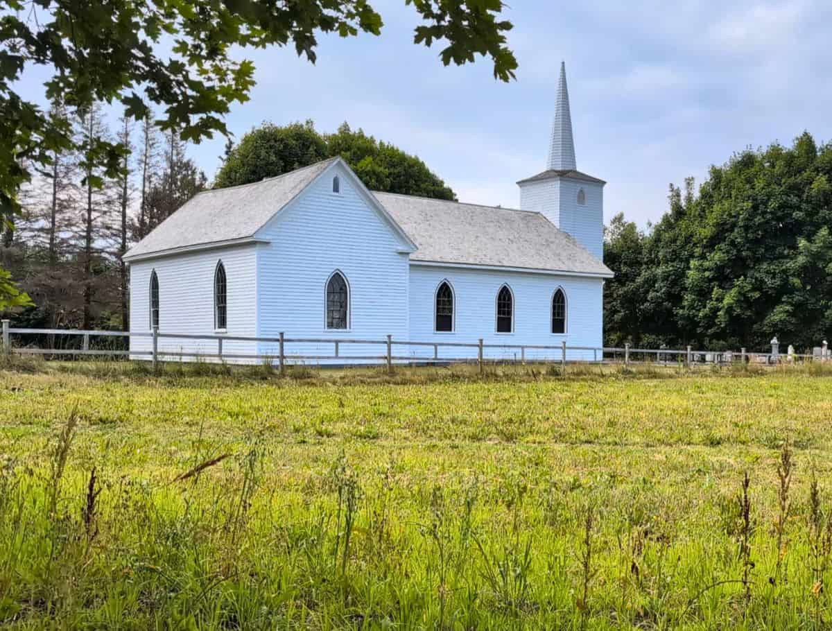 White steepled church at the Orwell Corner Historic Village with green field in foreground
