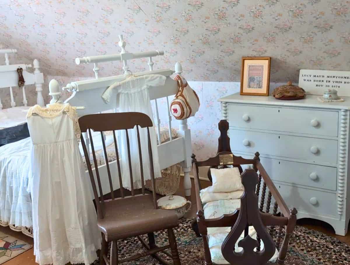 The room L.M. Montgomery was born, crowded with old bedroom furniture, baby clothes hanging and other bedroom items