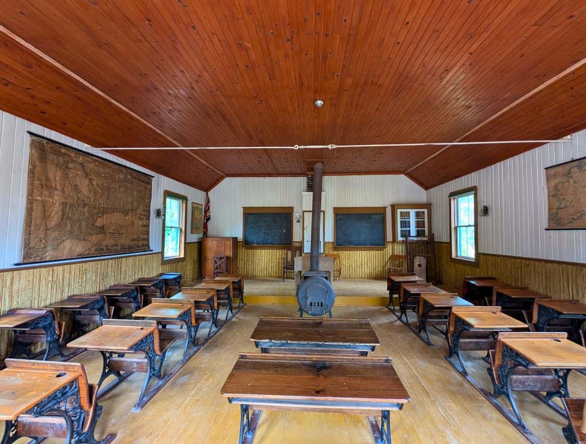 schoolhouse interior at simcoe county museum with desks, wood paneled walls, and firestove