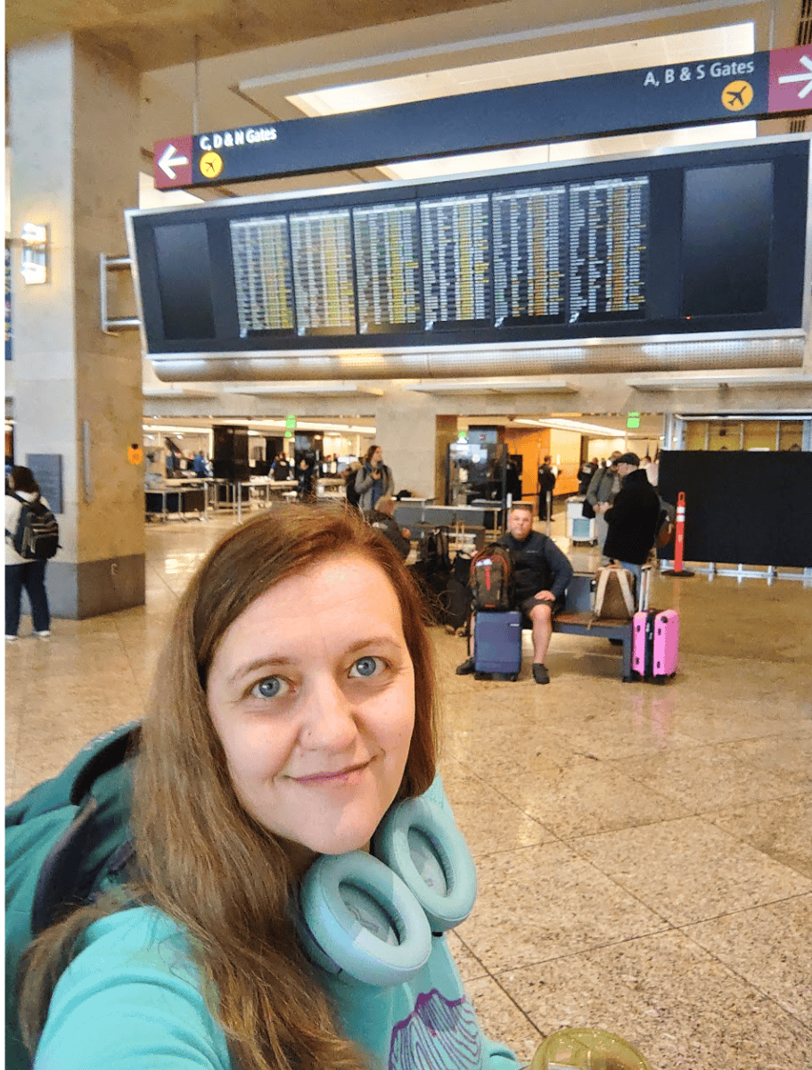 selfie of me at the airport with departure screen behind me
